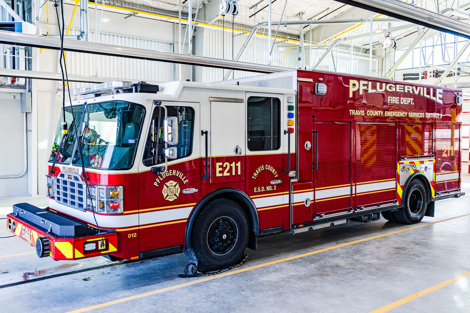 Red Pflugerville Fire Department Engine 211 pumper staged inside a fire station bay.