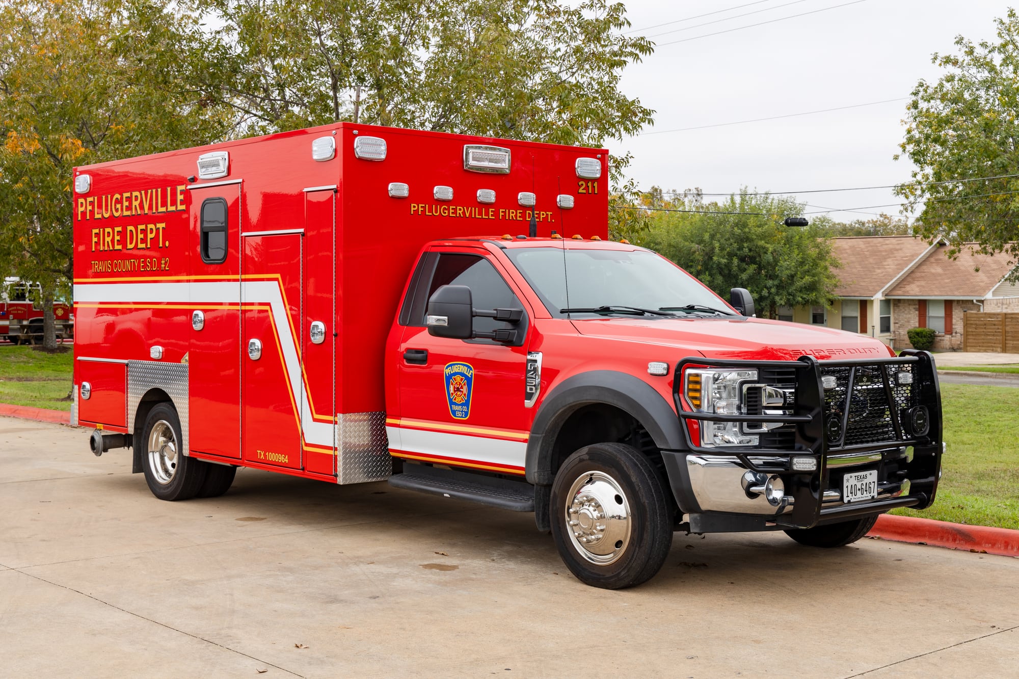 Red Pflugerville Fire Department Medic 211 ambulance parked on a station driveway.