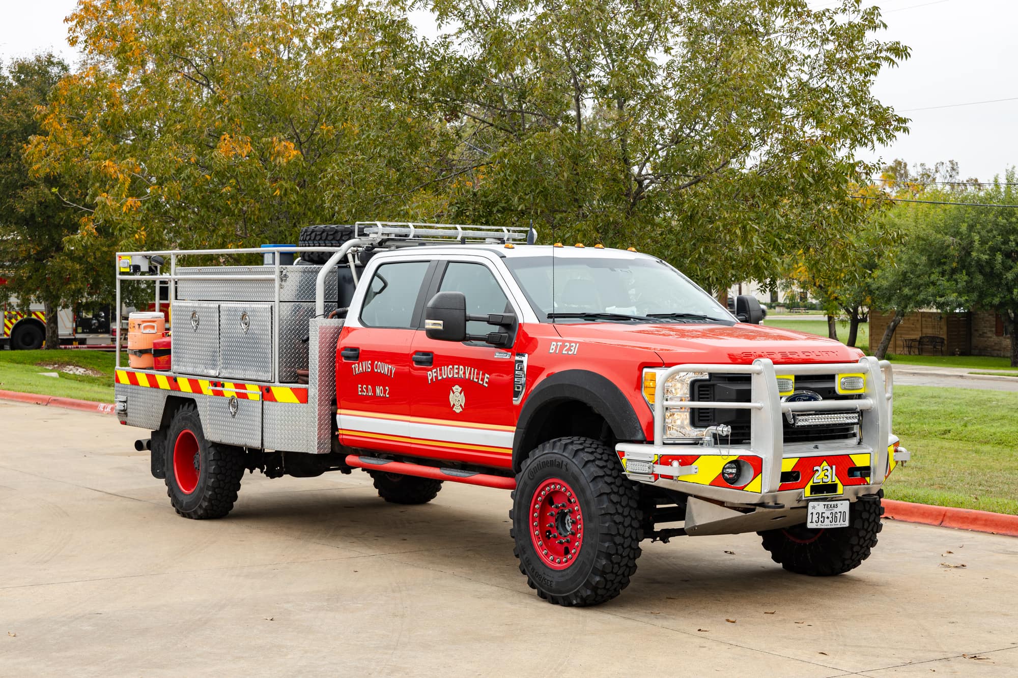Red Pflugerville Fire Department Brush 231 wildland truck with rear hose bed parked outdoors.