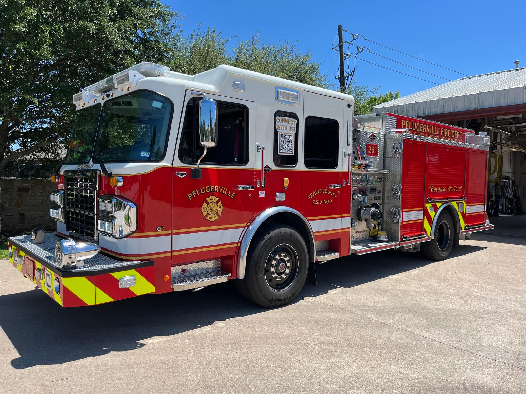 Red and white Pflugerville Fire Department Engine 231 pumper parked outside the station.