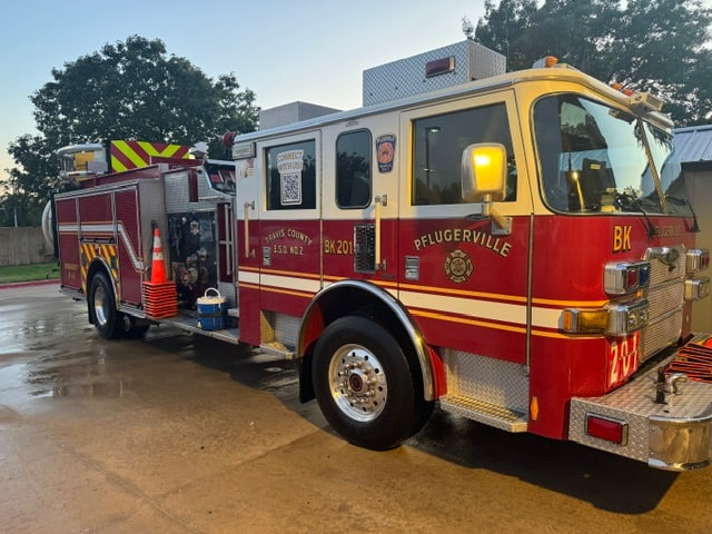 Pflugerville Fire Department Blocker 201 apparatus parked on wet pavement with warning lights visible.