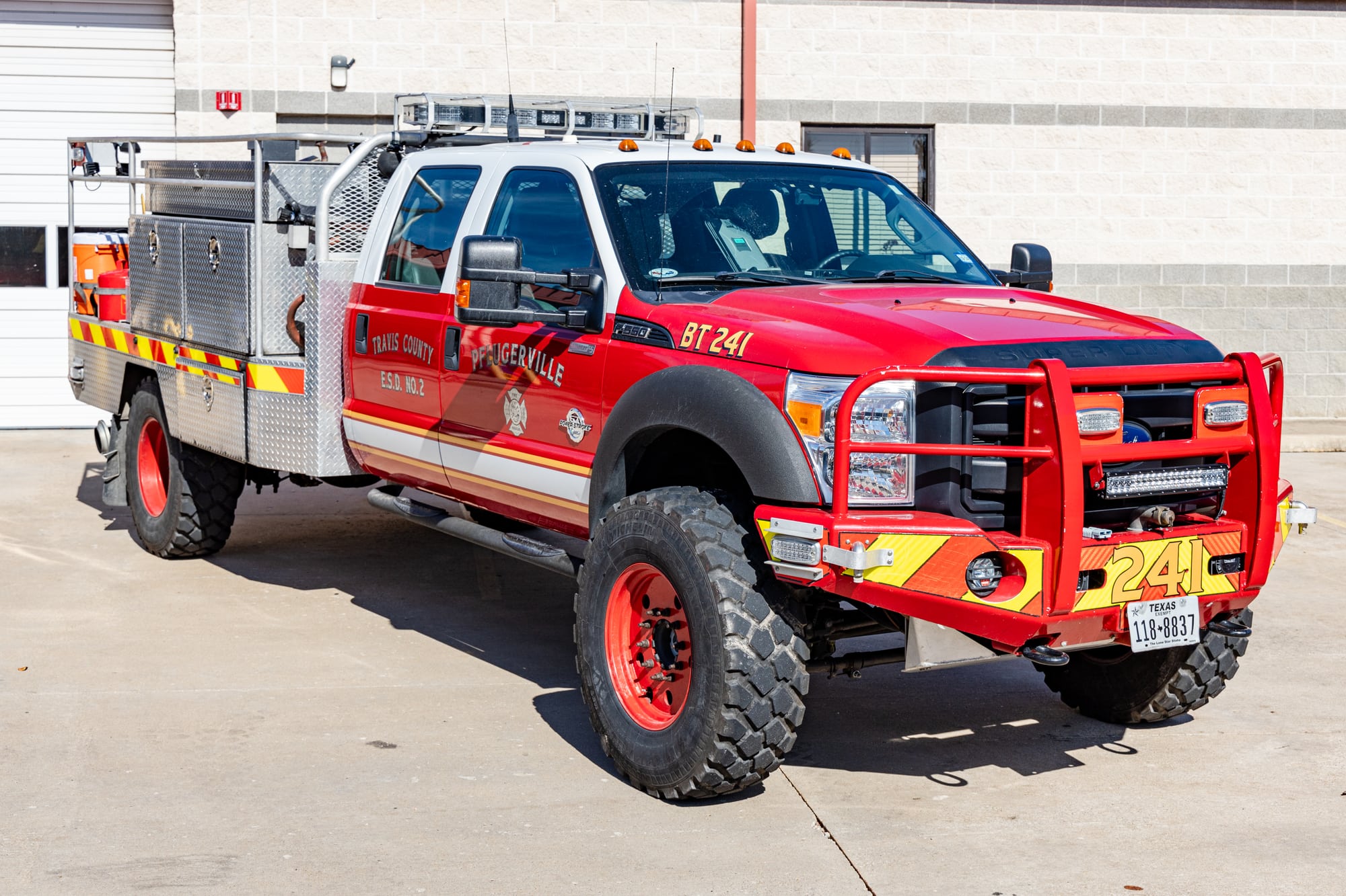 Red Pflugerville Fire Department Brush 241 wildland truck parked outside a station bay.