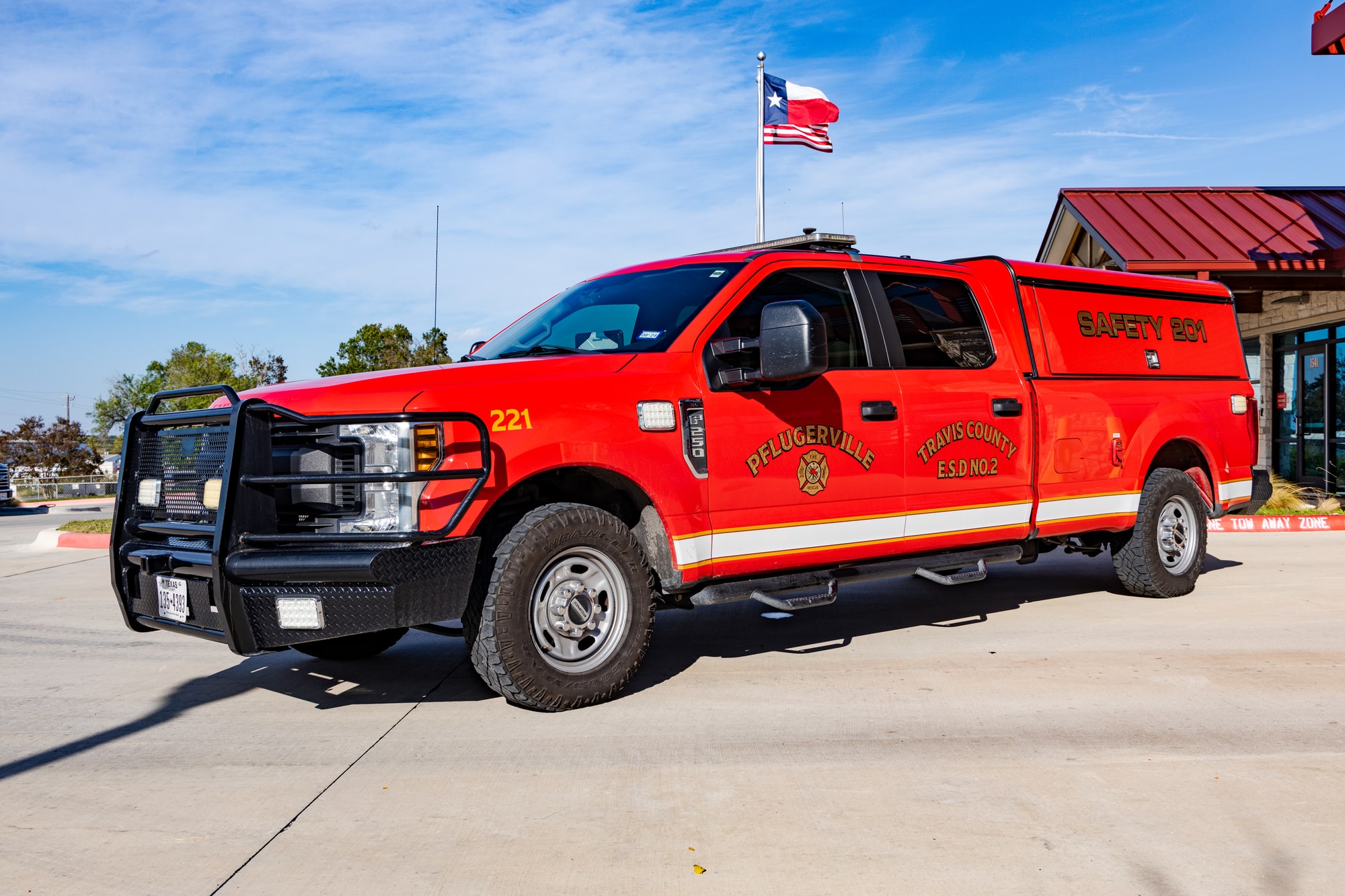 Red Pflugerville Fire Department Safety 201 pickup parked in front of a fire station.