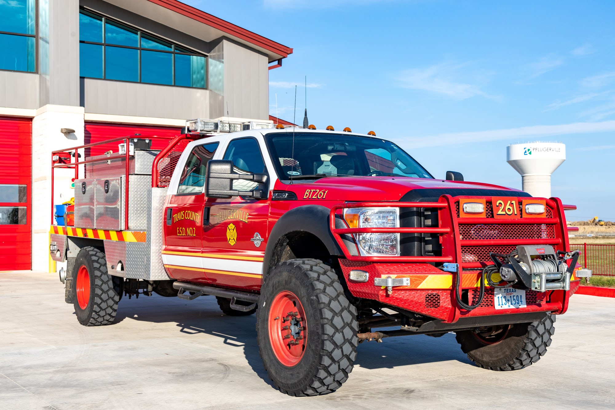 Red Pflugerville Fire Department Brush 261 wildland truck parked in front of a station.
