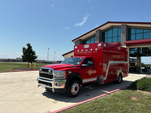 Red Pflugerville Fire Department Medic 261 ambulance parked near a station driveway.