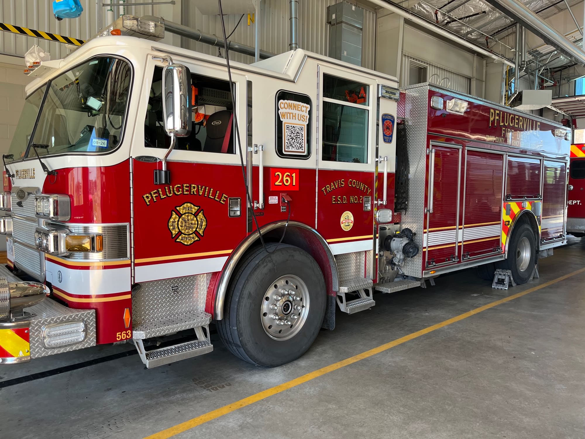 Red and white Pflugerville Fire Department Reserve Engine 270 pumper staged inside a fire station bay.
