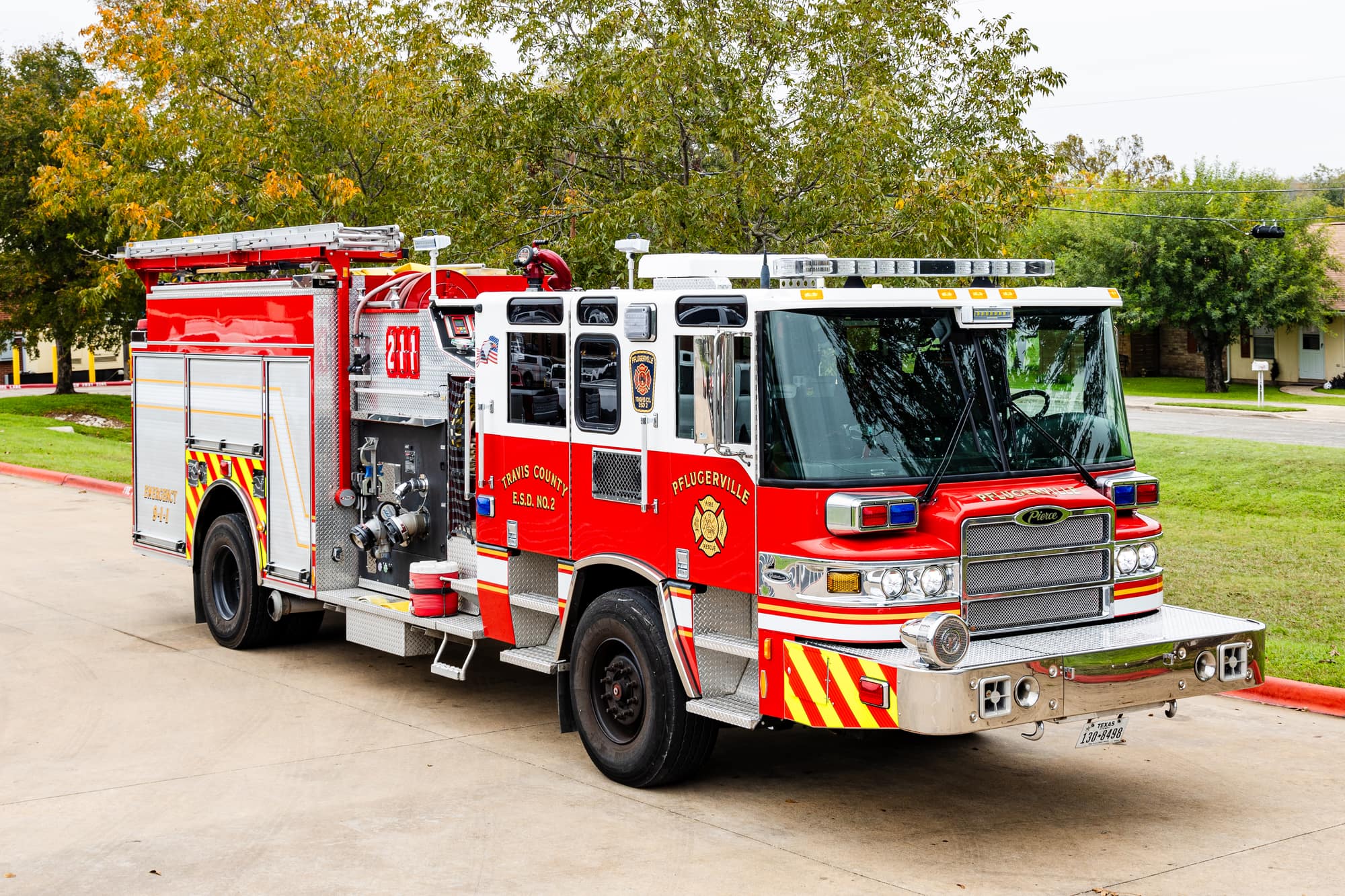 Red and white Pflugerville Fire Department Reserve Engine 280 pumper parked near a grassy area.