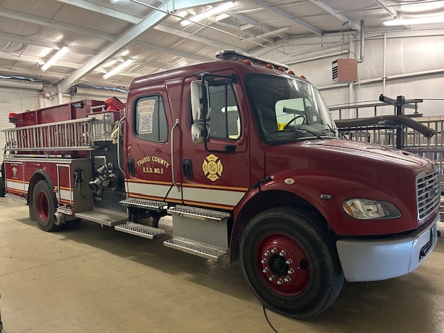 Maroon Pflugerville Fire Department Training Engine 205 parked indoors at the training field.